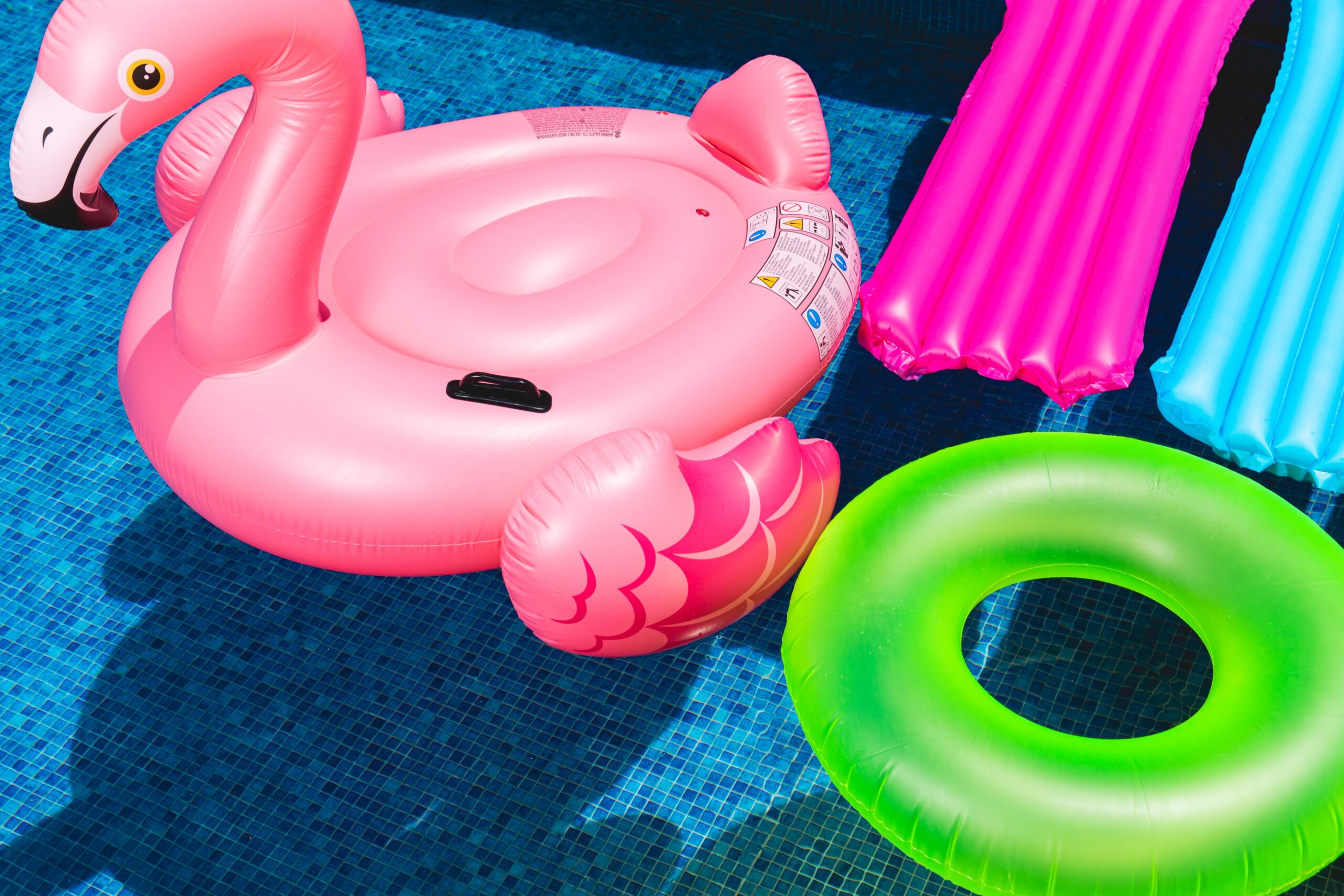 brightly colored pool floats in a sparkling blue pool
